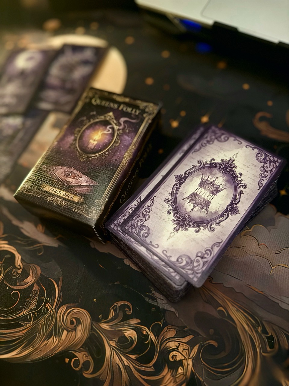 Queen's Folly illustrated box beside the stacked deck and ornate card backs